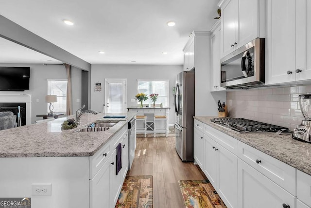 kitchen with a center island with sink, white cabinets, a sink, and stainless steel appliances