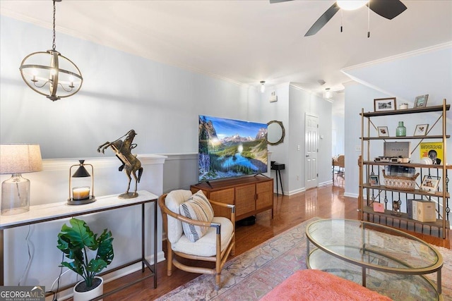 living room featuring hardwood / wood-style floors, ceiling fan with notable chandelier, and ornamental molding