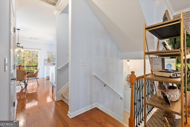 stairway featuring crown molding, sink, and wood-type flooring