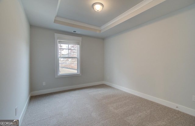 carpeted empty room with ornamental molding and a tray ceiling