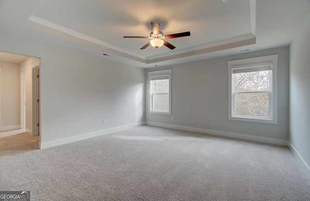 carpeted spare room featuring a raised ceiling and ceiling fan