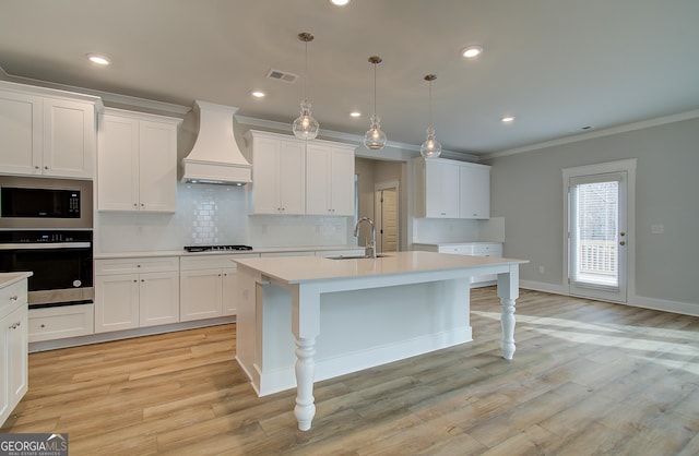 kitchen with built in microwave, oven, pendant lighting, a kitchen island with sink, and custom exhaust hood