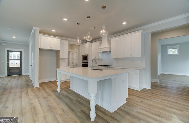 kitchen with white cabinets, an island with sink, hanging light fixtures, and custom exhaust hood