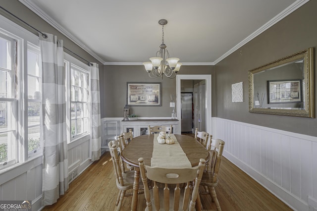 dining room with a notable chandelier, crown molding, and wood-type flooring