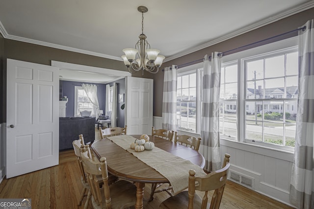 dining room with hardwood / wood-style flooring, crown molding, and a chandelier