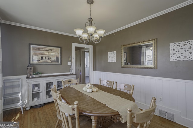 dining area with crown molding, hardwood / wood-style flooring, and a chandelier