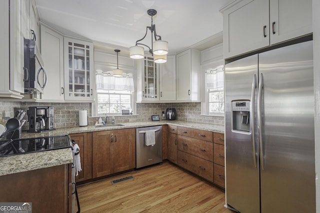 kitchen featuring appliances with stainless steel finishes, plenty of natural light, pendant lighting, and white cabinets