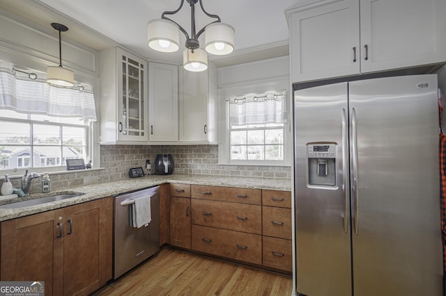 kitchen with sink, white cabinetry, backsplash, hanging light fixtures, and stainless steel appliances