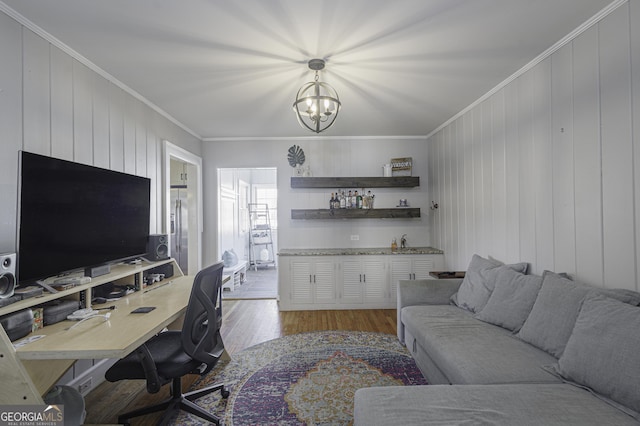 office space featuring a notable chandelier, light hardwood / wood-style flooring, ornamental molding, and indoor bar