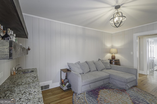 living room featuring ornamental molding, sink, dark wood-type flooring, and a chandelier