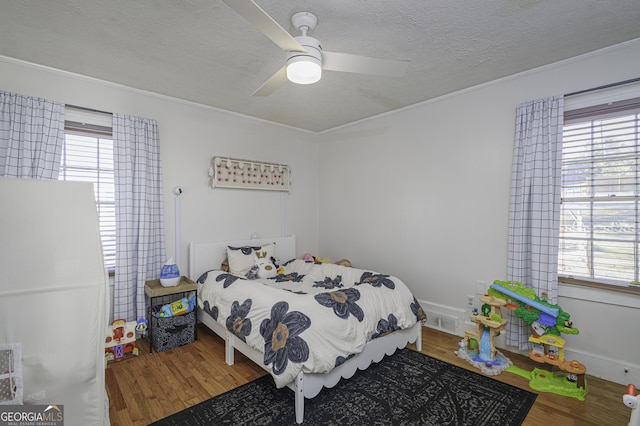 bedroom with hardwood / wood-style flooring, ceiling fan, crown molding, and a textured ceiling