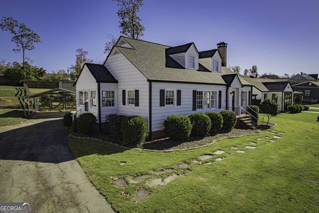 cape cod house featuring a front yard