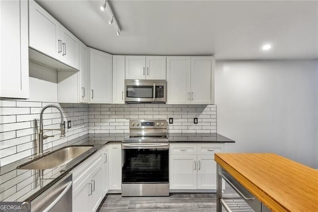 kitchen featuring appliances with stainless steel finishes, backsplash, sink, hardwood / wood-style flooring, and white cabinets