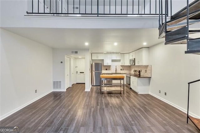 kitchen featuring dark wood-type flooring, sink, decorative backsplash, white cabinetry, and stainless steel appliances