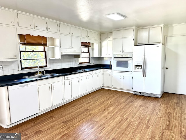 kitchen with white appliances, dark countertops, light wood-style floors, open shelves, and a sink