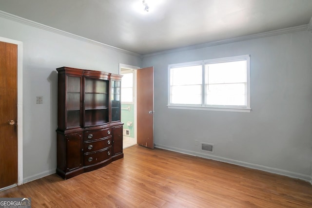 unfurnished bedroom featuring visible vents, crown molding, baseboards, and wood finished floors