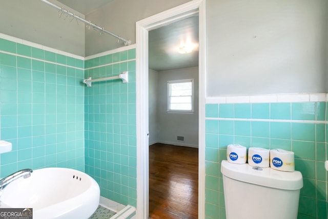 bathroom with a wainscoted wall, tile walls, toilet, and wood finished floors