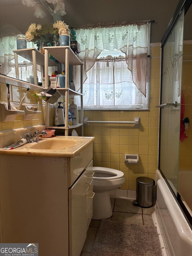 full bathroom featuring tile patterned flooring, toilet, tile walls, and a wealth of natural light