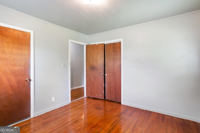 unfurnished bedroom featuring ornamental molding, wood finished floors, and baseboards