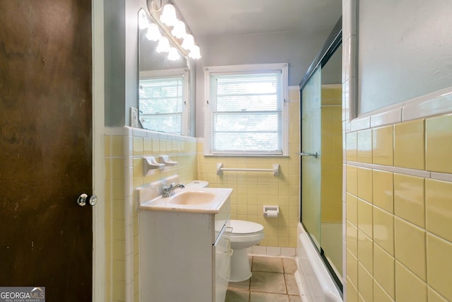 bathroom with wainscoting, toilet, tile patterned flooring, vanity, and tile walls