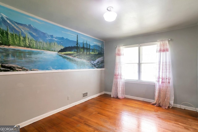 unfurnished room featuring wood finished floors, visible vents, and baseboards