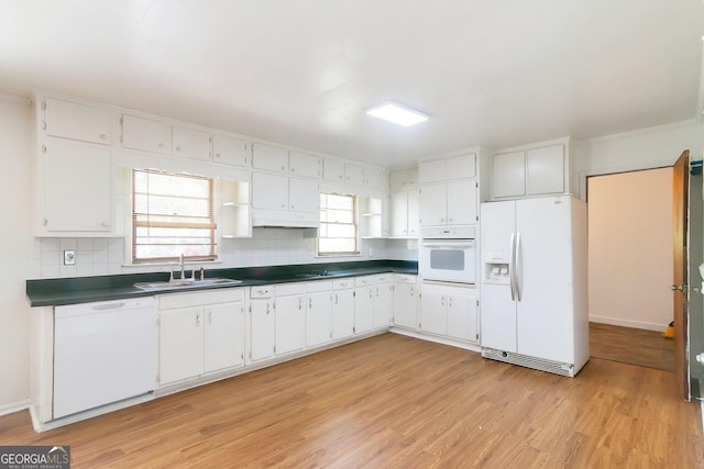 kitchen featuring white appliances, dark countertops, and white cabinets