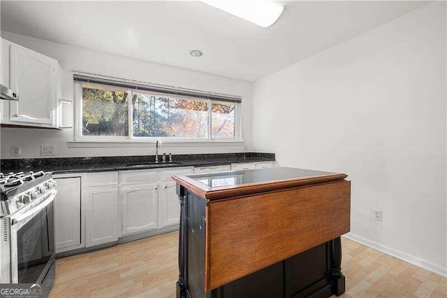 kitchen featuring white cabinets, light wood-type flooring, gas stove, and sink