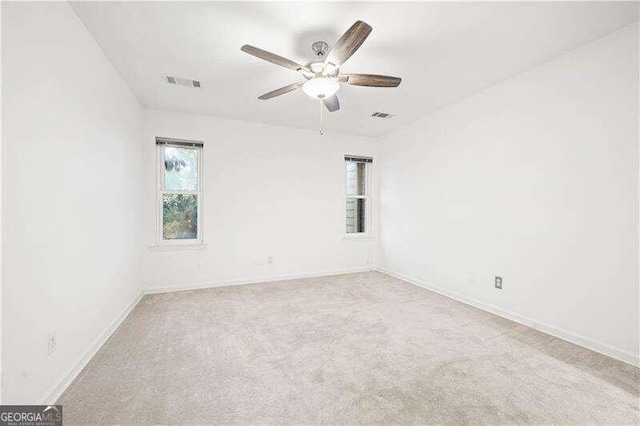 empty room featuring ceiling fan and light carpet