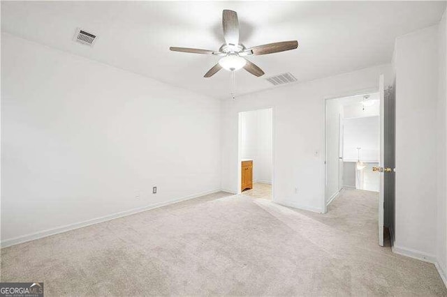 unfurnished bedroom featuring ceiling fan, light colored carpet, and ensuite bathroom