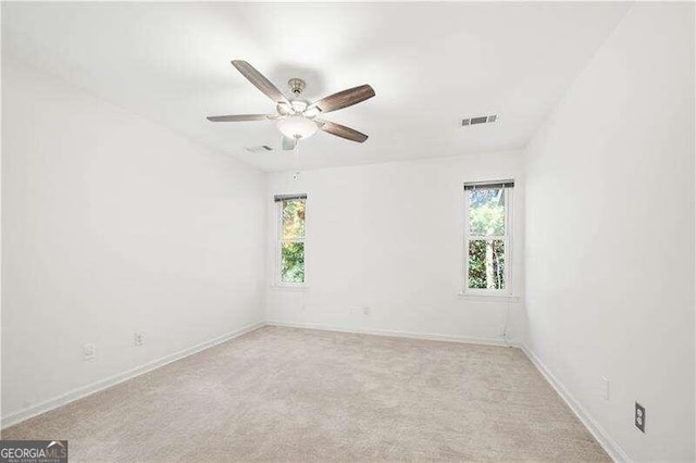 unfurnished room with light colored carpet, plenty of natural light, and ceiling fan