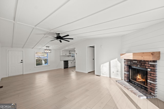 unfurnished living room featuring ceiling fan, light hardwood / wood-style floors, vaulted ceiling, and a brick fireplace