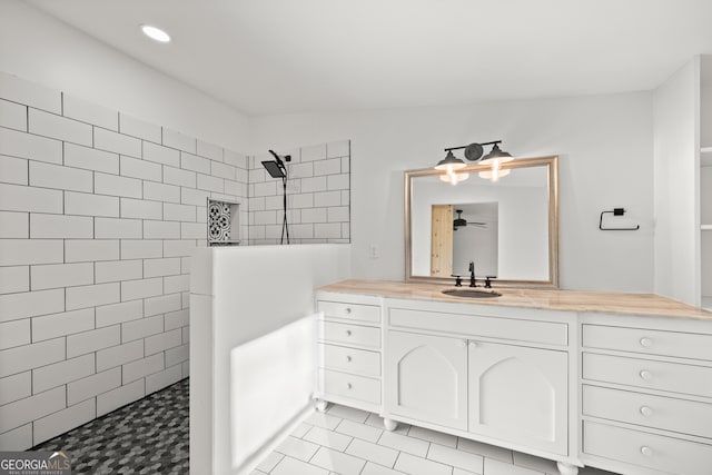 bathroom with tile patterned floors, ceiling fan, vanity, and tiled shower