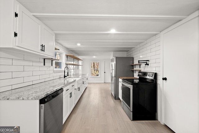 kitchen with decorative backsplash, light hardwood / wood-style flooring, white cabinets, and appliances with stainless steel finishes