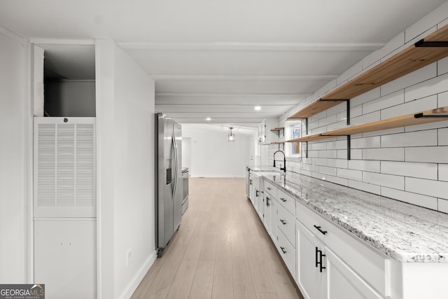 kitchen with white cabinetry, light stone counters, stainless steel refrigerator with ice dispenser, backsplash, and light hardwood / wood-style floors