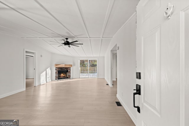 unfurnished living room with ceiling fan, a fireplace, and light hardwood / wood-style flooring