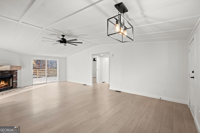 unfurnished living room with ceiling fan, light hardwood / wood-style floors, lofted ceiling, and a brick fireplace