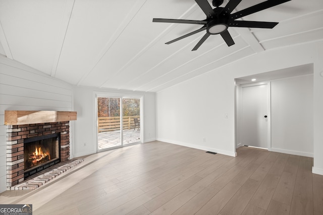 unfurnished living room with hardwood / wood-style floors, vaulted ceiling with beams, ceiling fan, and a brick fireplace