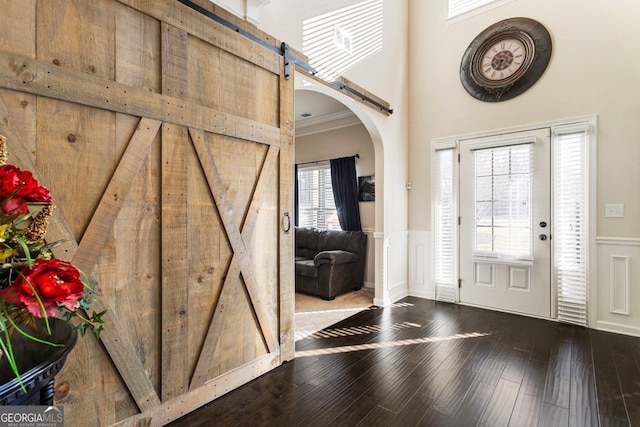 entryway with hardwood / wood-style floors, a barn door, and ornamental molding