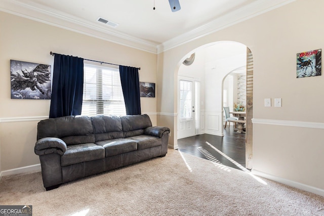 carpeted living room featuring crown molding, ceiling fan, and a healthy amount of sunlight