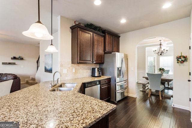 kitchen featuring dark brown cabinetry, sink, dark hardwood / wood-style floors, decorative light fixtures, and appliances with stainless steel finishes