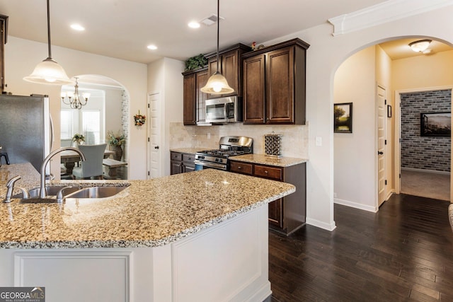 kitchen featuring light stone countertops, sink, stainless steel appliances, dark hardwood / wood-style flooring, and decorative light fixtures