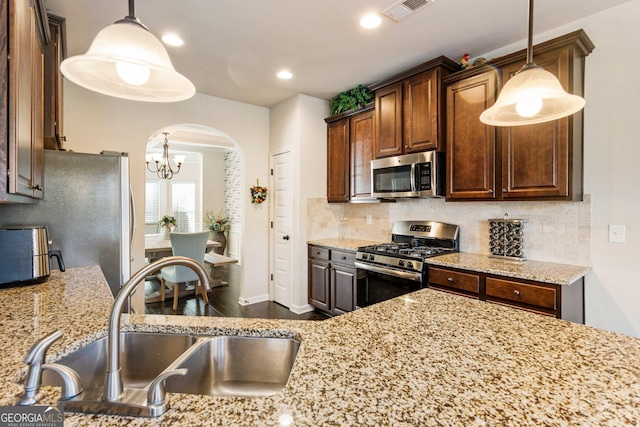 kitchen featuring sink, stainless steel appliances, decorative light fixtures, and an inviting chandelier