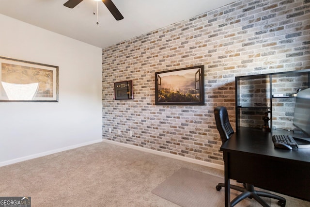 unfurnished office with carpet flooring, ceiling fan, and brick wall