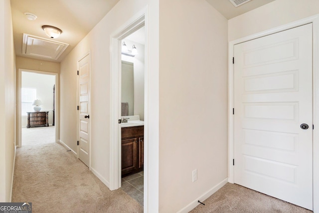 corridor featuring light colored carpet and sink