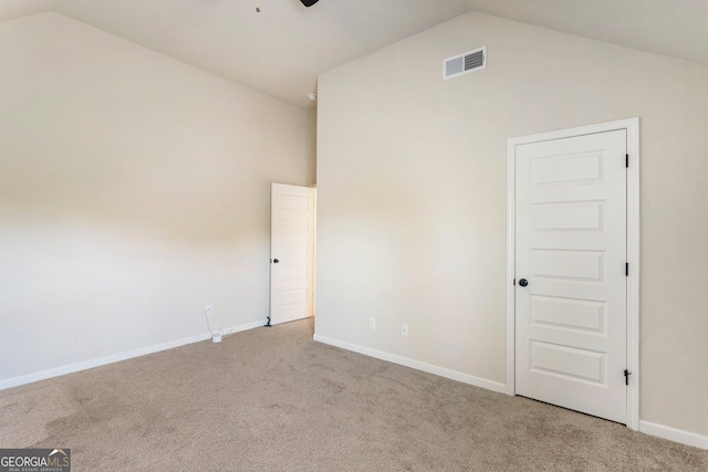 carpeted empty room featuring lofted ceiling