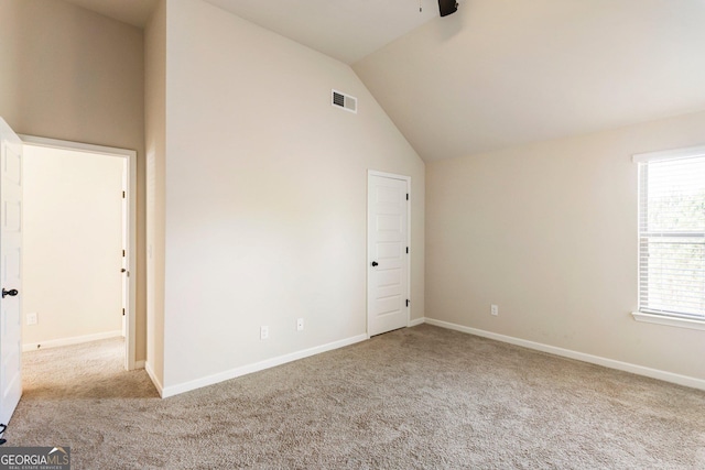 spare room featuring light carpet and vaulted ceiling