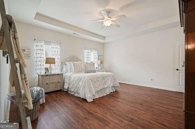 bedroom featuring a tray ceiling, ceiling fan, and dark hardwood / wood-style flooring