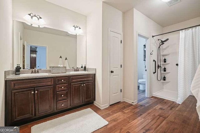 bathroom with a shower with curtain, toilet, vanity, and hardwood / wood-style flooring