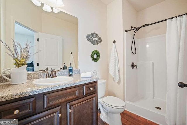 bathroom with a shower with shower curtain, wood-type flooring, vanity, and toilet