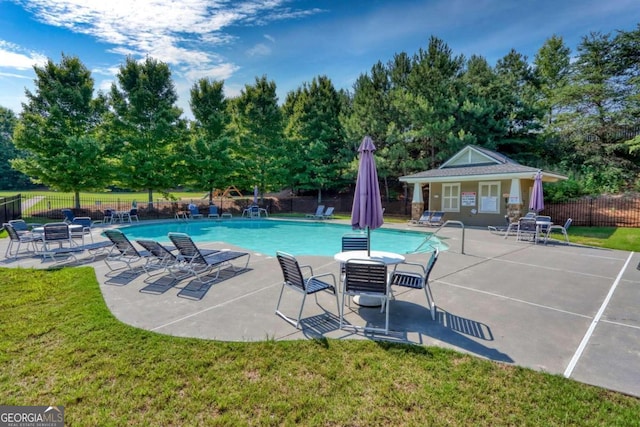 view of pool featuring a lawn, a patio area, and an outbuilding